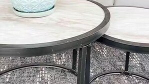 Ein runder Tisch mit einem Blumentopf und einem weißen Kissen mit blauen Streifen.