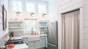 A kitchen with a stove, sink, and refrigerator, wooden walls, and pendant lights. - Pigs Fly in Burton just minutes to Round Top Antiques Shopping and Dining (Burton)