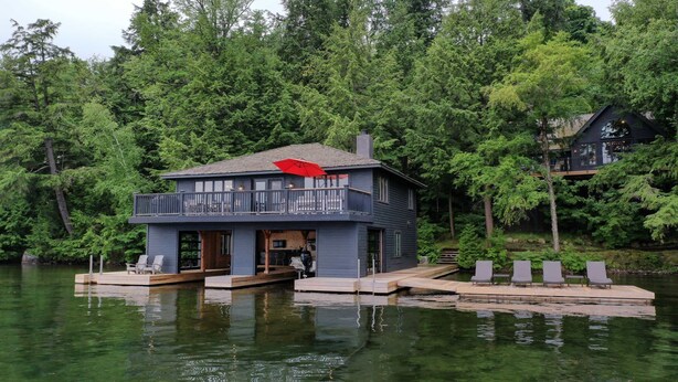 A house on stilts over water, with a deck and outdoor seating.