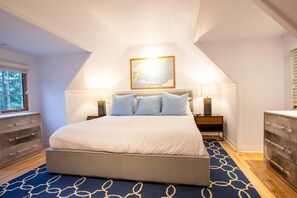 Ein Schlafzimmer mit einem großen Bett, zwei Nachttischen, einer Kommode und einem Fenster.