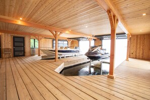 Une cabane en bois avec un sauna, une petite piscine et un bateau amarré à l’extérieur.