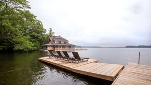 A lakeside cabin with a dock and lounge chairs.