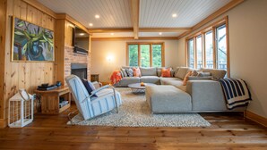 A spacious living room with a fireplace, a large window, and a cozy seating area.