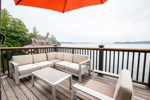 Eine Terrasse mit einem beigefarbenen Ecksofa, einem kleinen Tisch und einem Sessel.