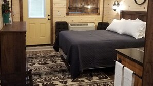 Een gezellig slaapkamer met een bed, een bureau, een stoel, een plafondventilator, een raam met jaloezieën en een spiegel aan de muur.