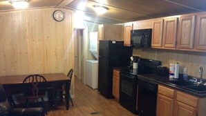 Une cuisine compacte dotée de meubles en bois, d’un four à micro-ondes, d’un réfrigérateur et d’un coin repas avec une table et des chaises.