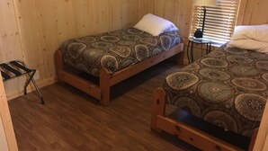 Une pièce avec deux lits en bois, une petite table et une chaise.