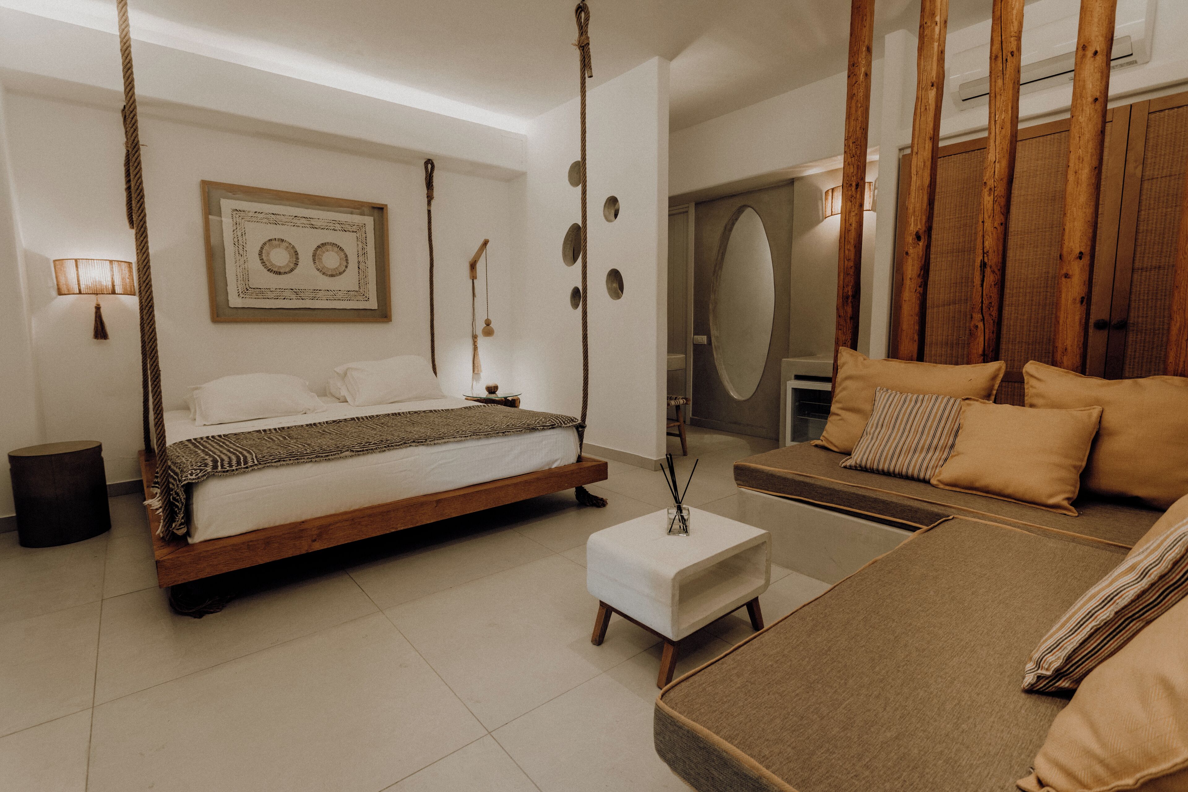 Une chambre à coucher avec un lit en bois, un canapé, une petite table et un miroir.