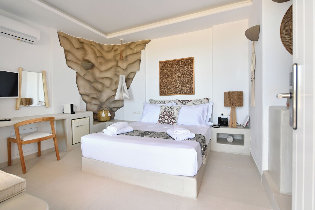 A modern bedroom with a bed, bedside table, lamp, and a mounted artwork.