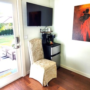 Ein Zimmer mit einem Sessel, einer Kaffeemaschine, einem Fernseher und einem Bild an der Wand.