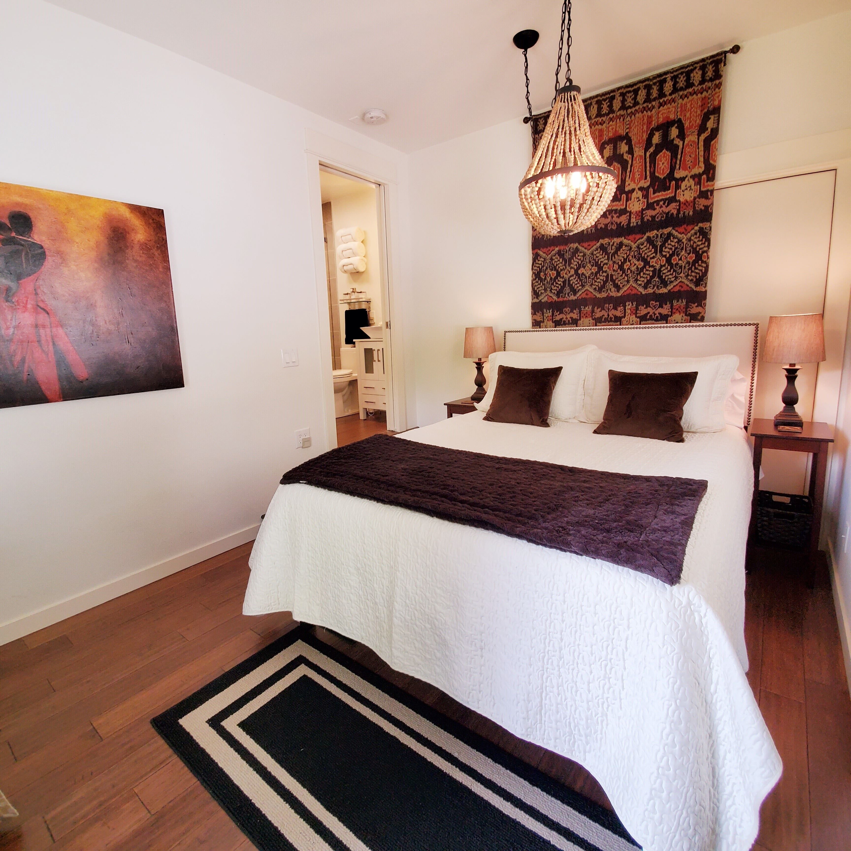 Une chambre à coucher avec un grand lit, un lustre, une tapisserie et un tableau au mur.