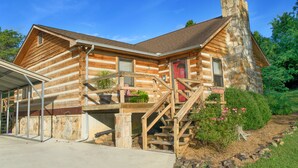 A log cabin with a stone chimney, wooden staircase, and a covered porch. - Log home on 50 acres. Private, convenient, beautiful. A little bit of paradise. (Knoxville)
