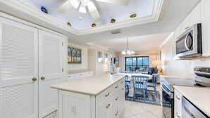 A modern kitchen with white cabinetry, a central island, and a ceiling fan.