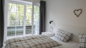 A bedroom with two beds, a nightstand, a wall-mounted lamp, and a heart-shaped decoration. - Landcafé Neumann (Bad Zwischenahn)