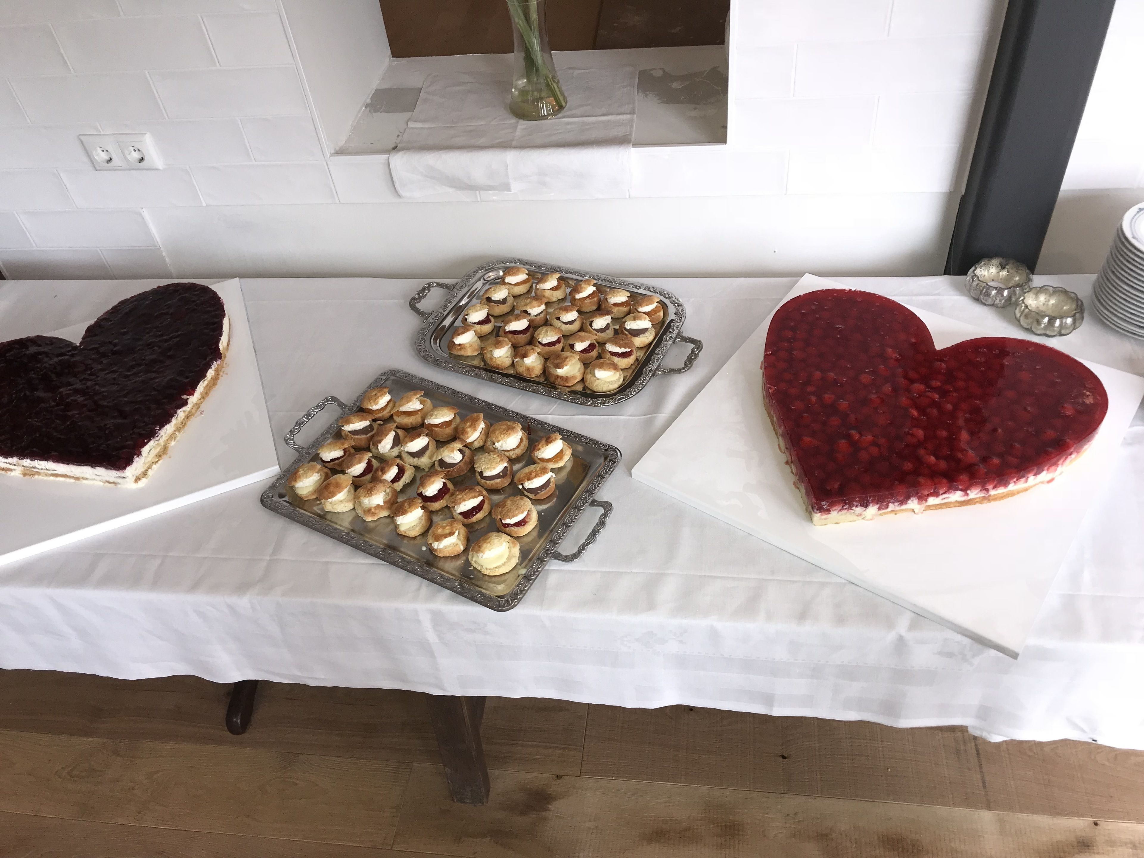 Una mesa con postres y pasteles, incluyendo un pastel con forma de corazón y pequeñas golosinas.