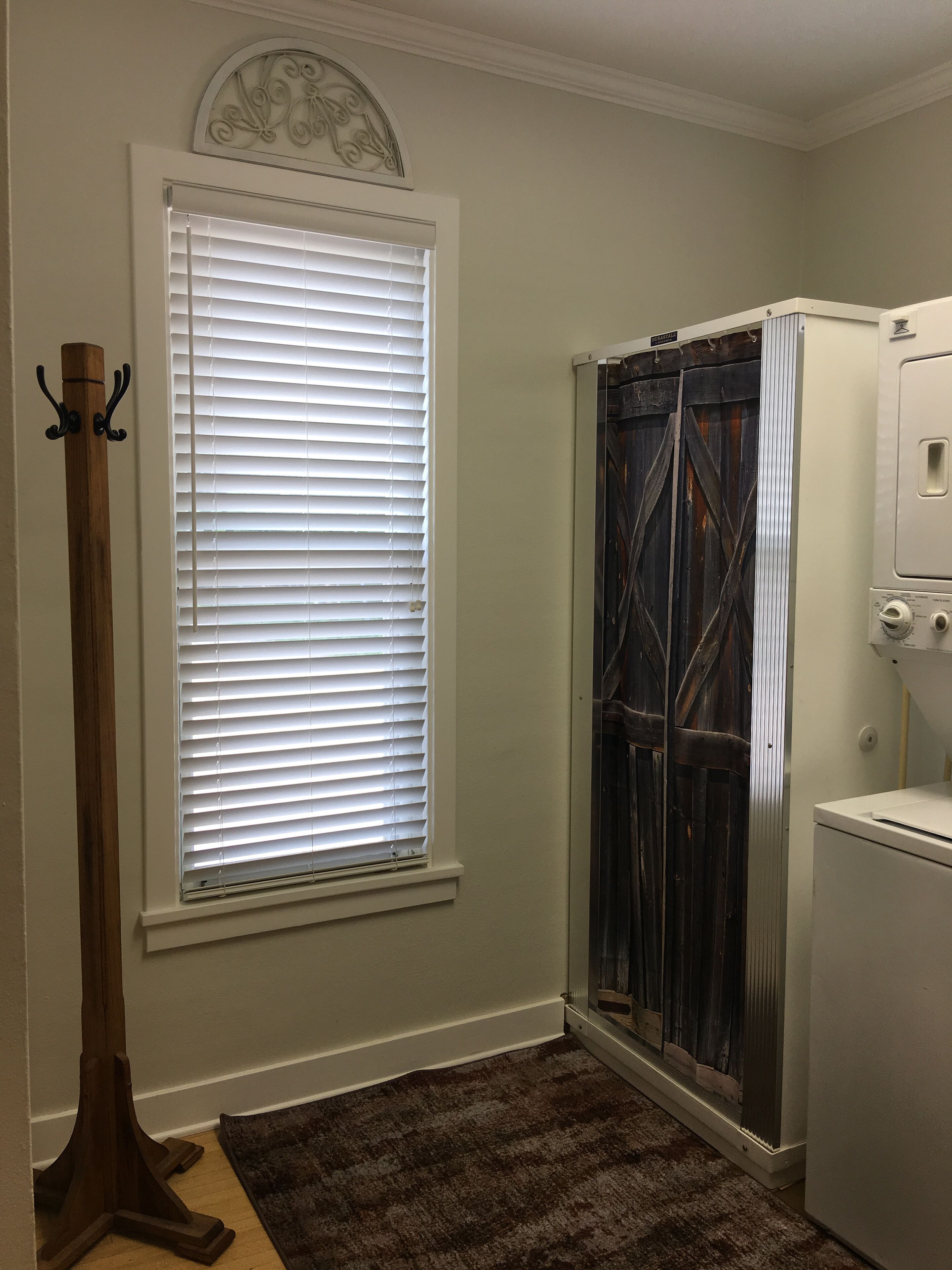 A bathroom with a shower, a towel rack, and a wooden coat stand.