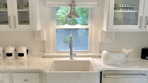A kitchen with white cabinetry, a window above the sink, and a dish drying rack. - Renovated cottage 1 mile to beach in Chatham! (Chatham)