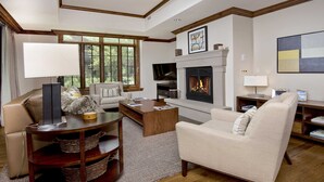 A living room with a fireplace, a television, and a bookshelf. - Vail Ritz Carlton Residence with air conditioning! Luxurious Hot Tub/Amenities (Vail)