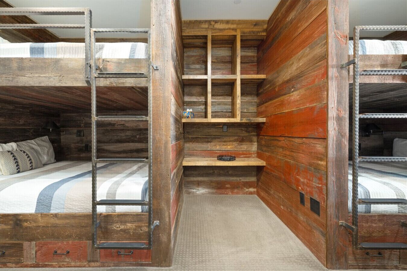 A rustic cabin-style room with bunk beds, a small desk, and a ladder.
