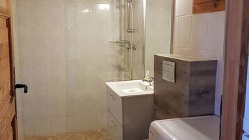 A compact bathroom with a shower, toilet, and washing machine.