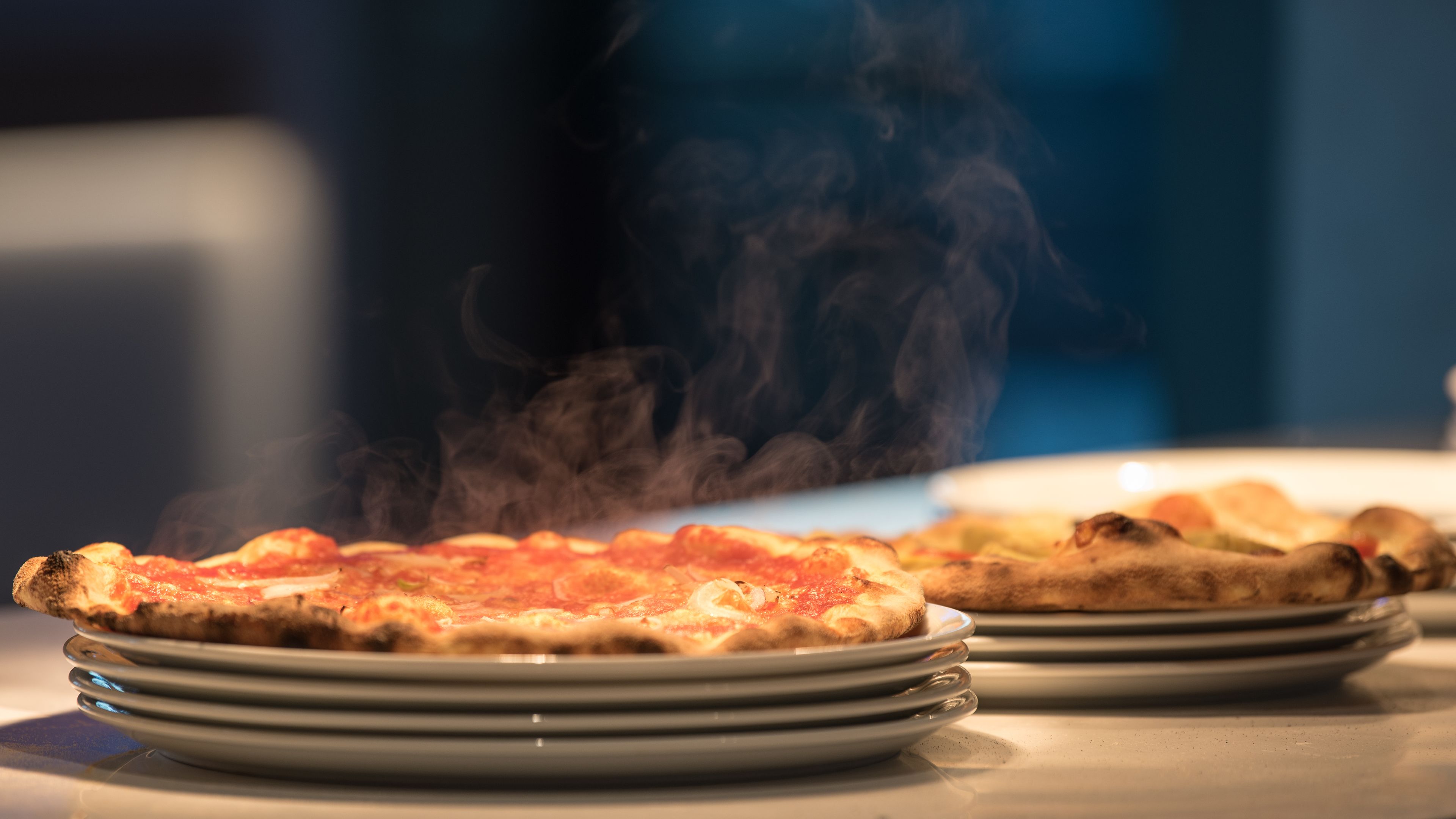 A stack of pizzas with visible steam, indicating they are freshly cooked.