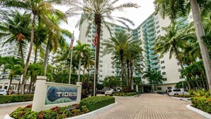 A hotel entrance with a sign reading 'The Tides 3801', surrounded by palm trees and a paved walkway. - Beachfront Apt | Hollywood, 10th Floor + Pool (Hollywood)