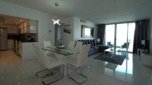 A modern living space with a dining area, kitchen, and seating area. - Beachfront Apt | Hollywood, 10th Floor + Pool (Hollywood)