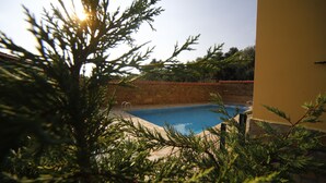 Piscina rodeada de vegetación y muros de piedra.