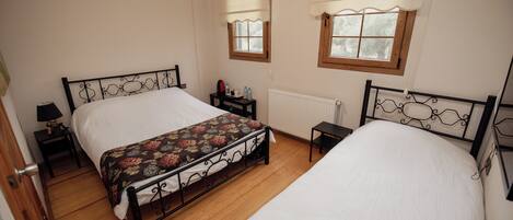 A bedroom with two beds, a nightstand, a dresser, and a window with a view.