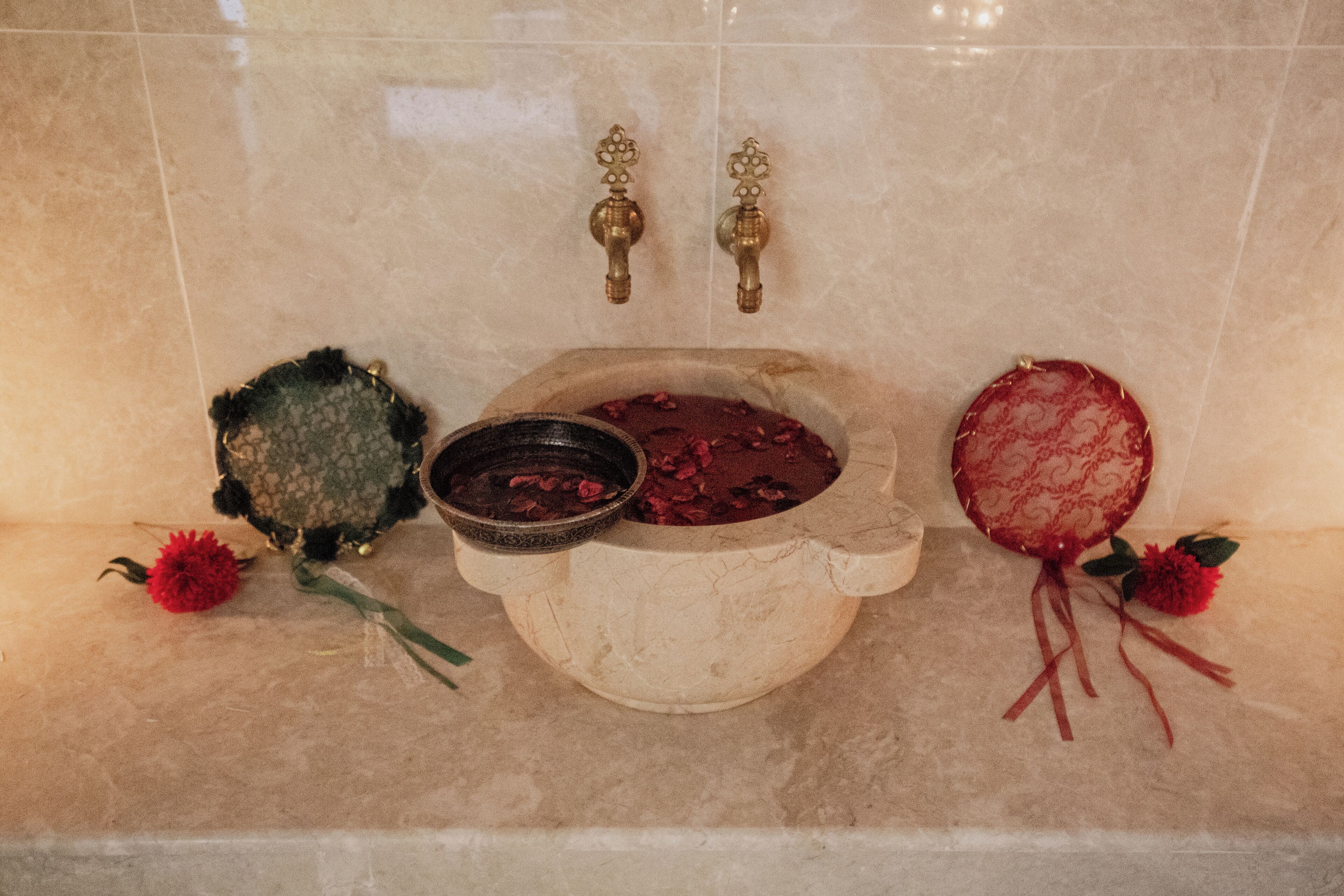 Une baignoire agrémentée d’un lavabo décoratif, d’un petit récipient et d’un arrangement floral.