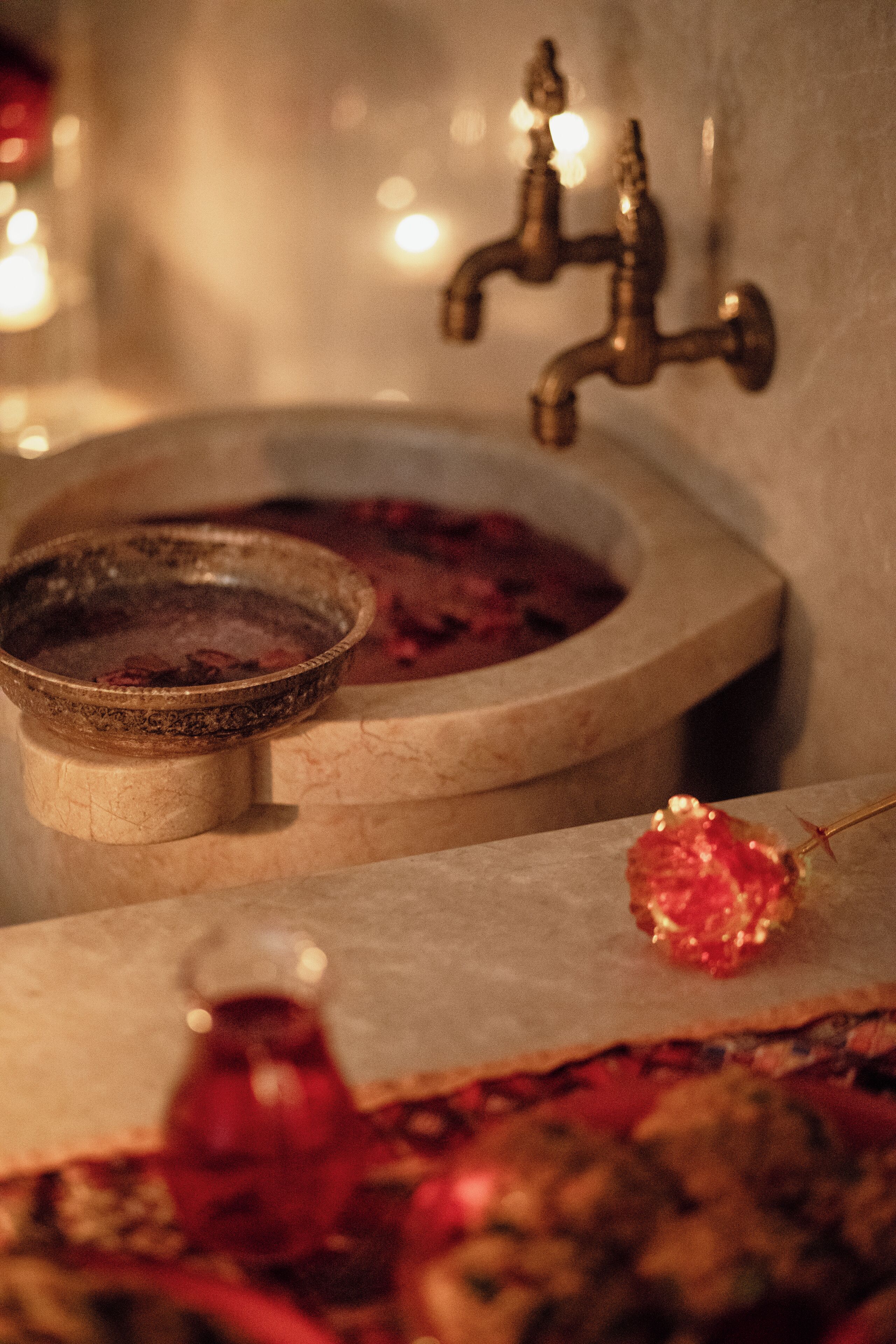 Un baño con lavabo, un recipiente y una botella de líquido rojo.