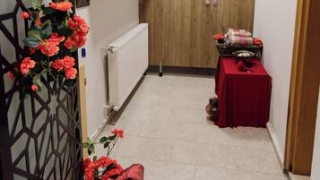 A narrow hallway with a radiator, a wooden door, and a table with a red tablecloth.