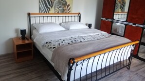 A bed with a metal frame, white bedding, and a zebra painting on the wall. - Ivan's holiday home (Zemunik Donji)