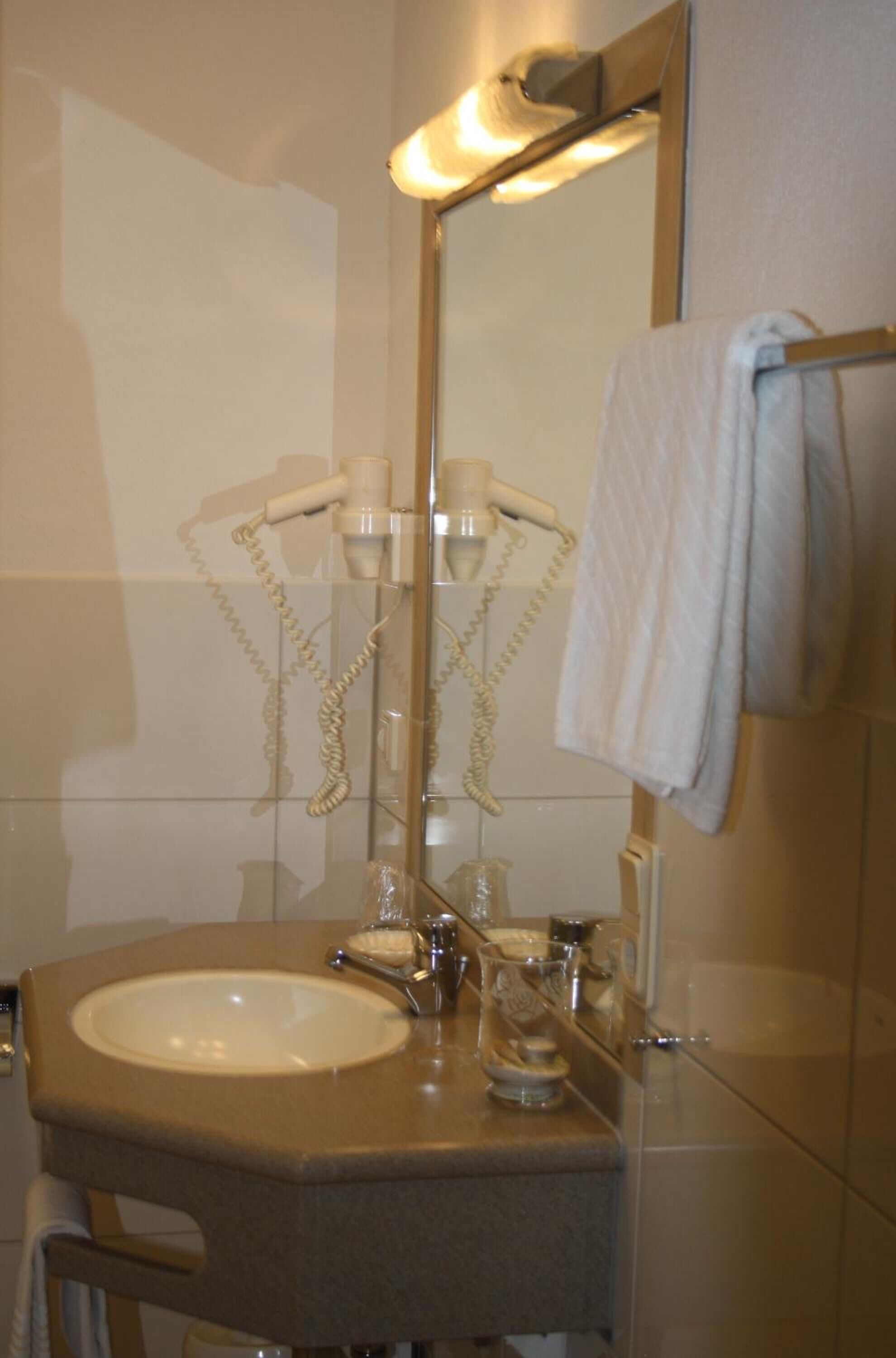 Un baño con lavamanos, espejo, toallero y ducha con mampara de vidrio.