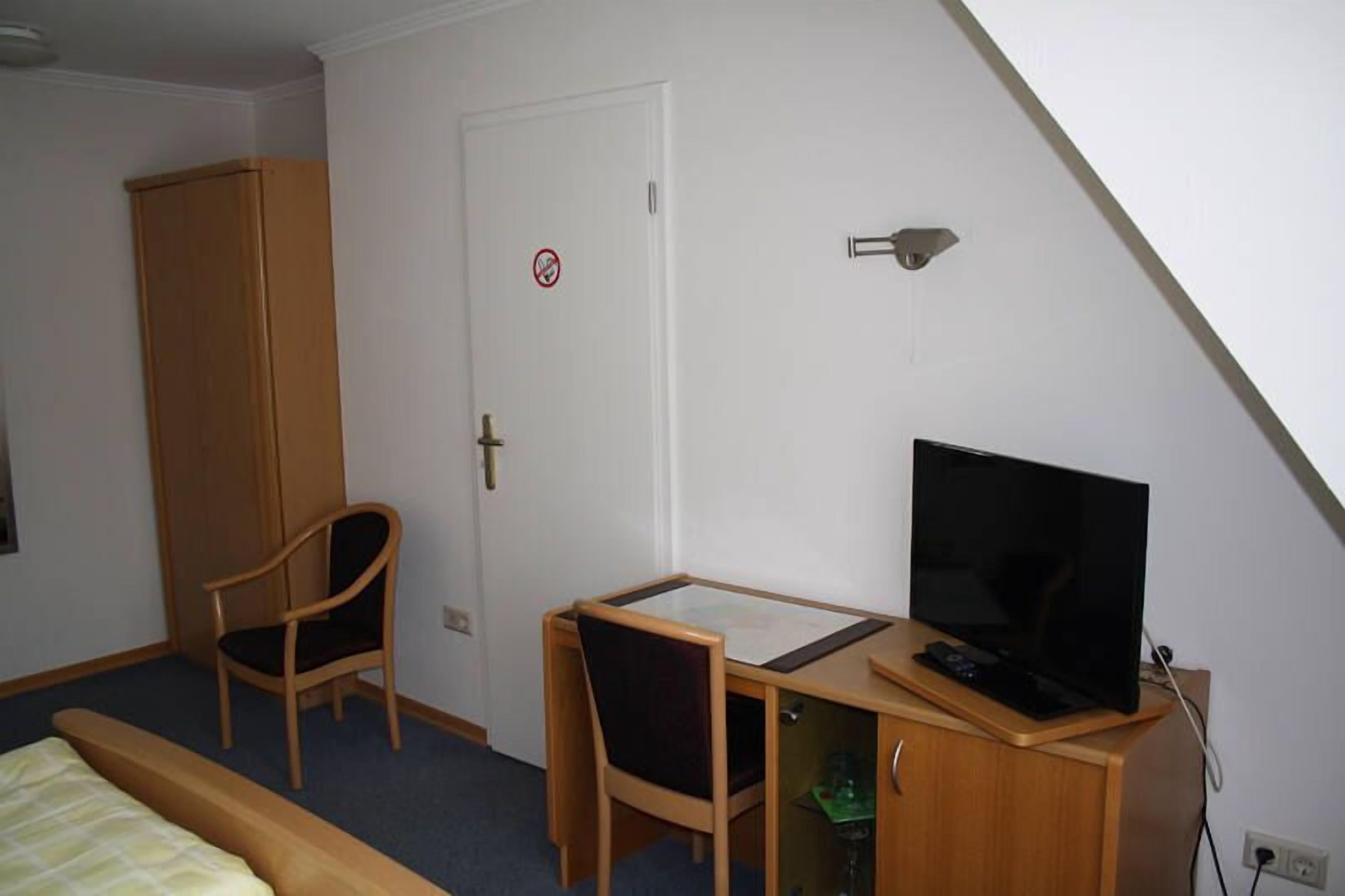 Une chambre à coucher comprenant un lit, un bureau avec une chaise, une télévision et une armoire.