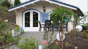 A house with a covered porch, a door, and a small garden with plants and flowers. - Pension Allebrodt (Lennestadt)
