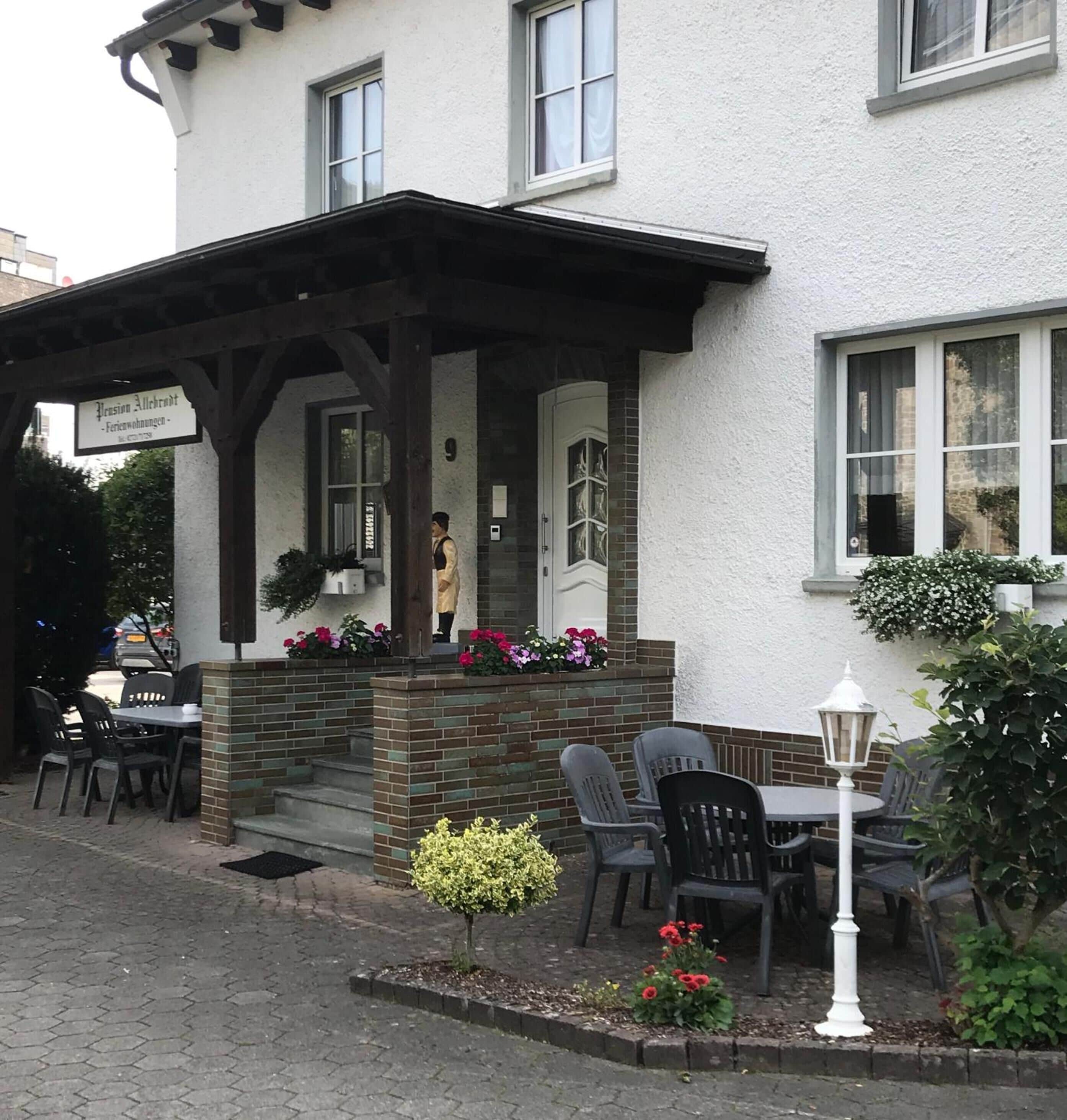 A building with a covered entrance, outdoor seating, and a small garden area.