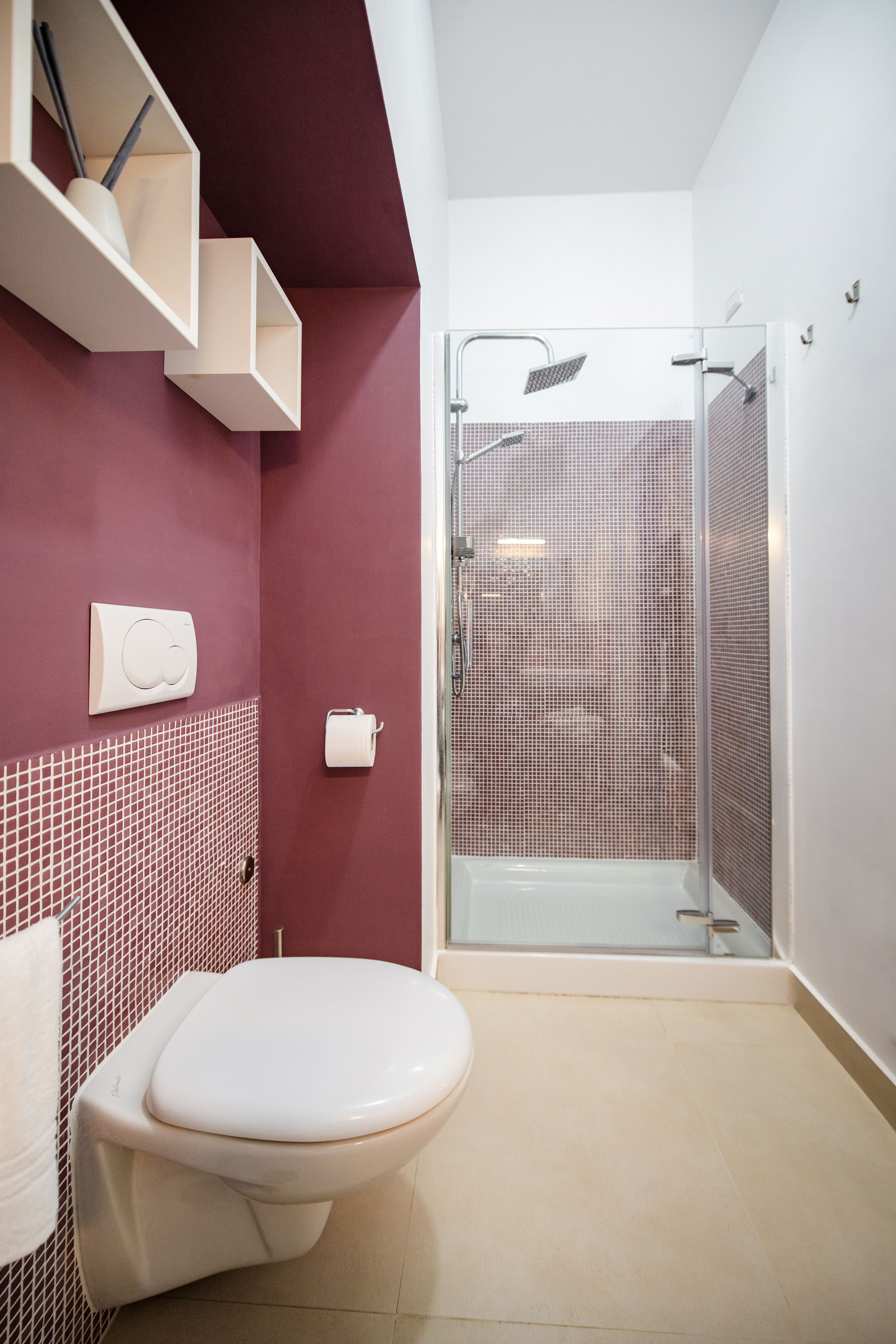 A bathroom with a toilet, a shower, and a tiled wall.