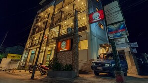A multi-story hotel with balconies, a visible entrance, and a parked vehicle. - Hotel Zenturia (Boac)