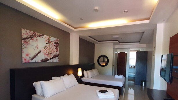 A hotel room with two beds, a large painting, a TV, and a hallway leading to another room. - Hotel Zenturia (Boac)