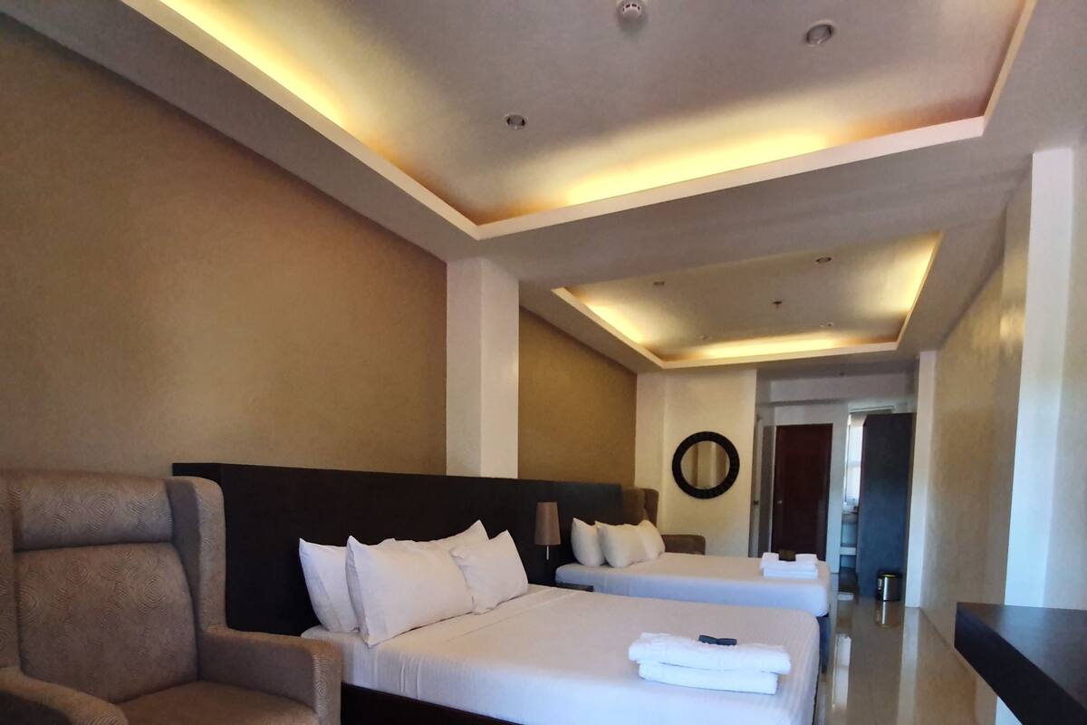 Una habitación de hotel con una cama grande, una silla y un espejo en la pared.