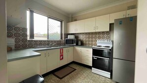 A compact kitchen with a microwave, stove, and refrigerator. - Seabreeze 6 - Opposite Tuncurry Bowling Club! (Tuncurry)