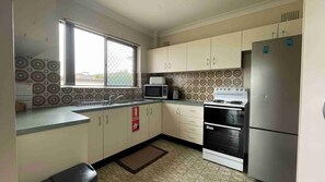 Una cocina compacta con microondas, estufa y refrigerador.