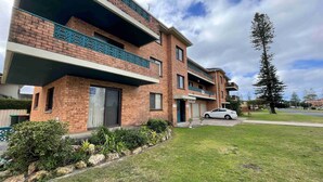 A multi-story residential building with brick facades, balconies, and a white car parked in front. - Seabreeze 6 - Opposite Tuncurry Bowling Club! (Tuncurry)