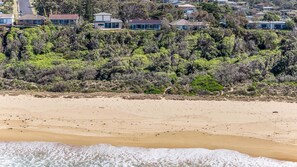 A beach with waves, a sandy shore, and a dense forest in the background. - The Breakers - Bunga Street 49 (BERMAGUI)