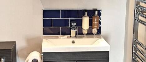 A modern bathroom with a dark wood vanity, a white sink, and a mirror above.