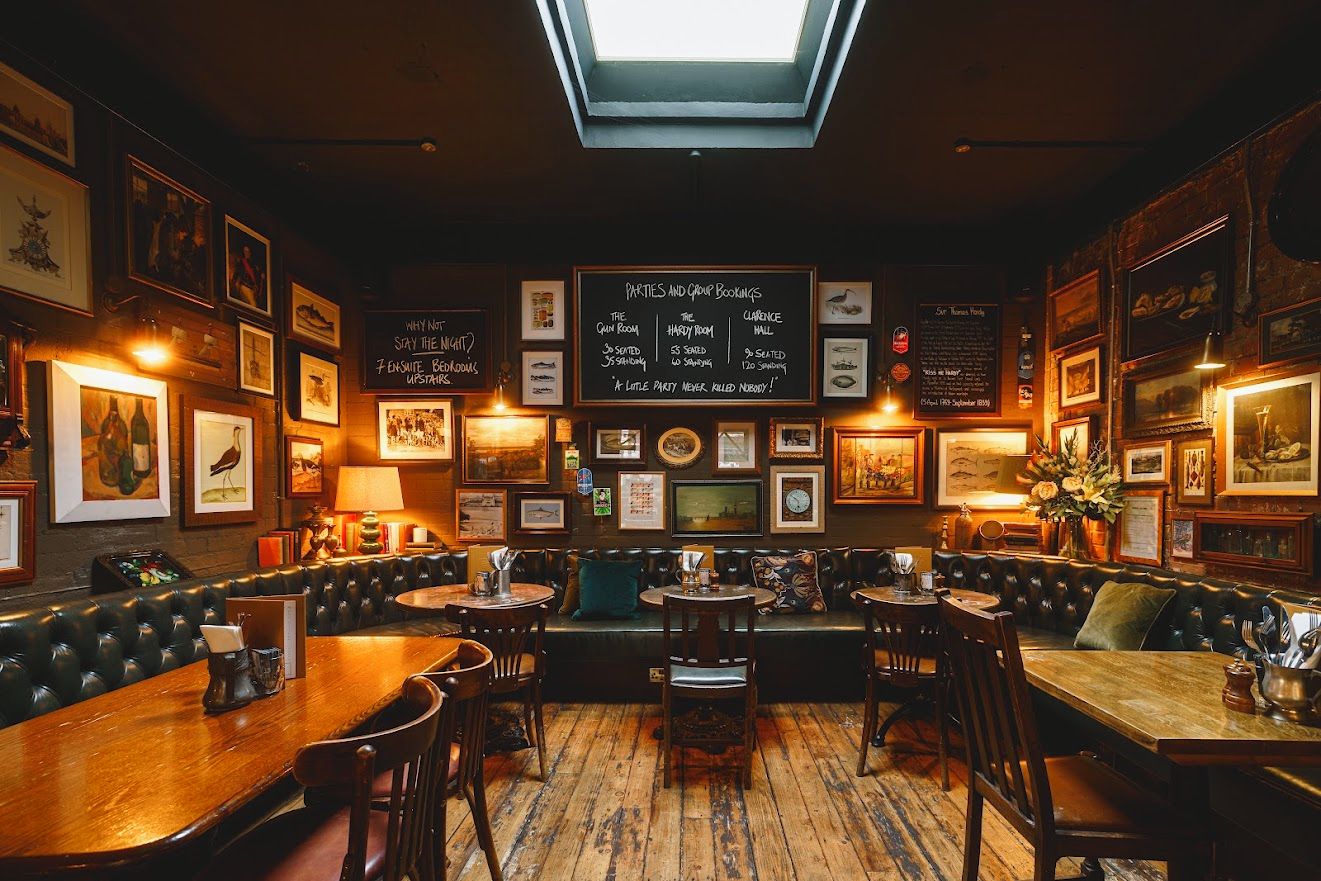 A cozy restaurant with wooden tables and booths, framed pictures on the walls, and a chalkboard menu.