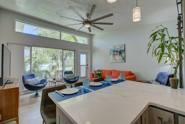 A modern kitchen with a large island, dining area, and seating.