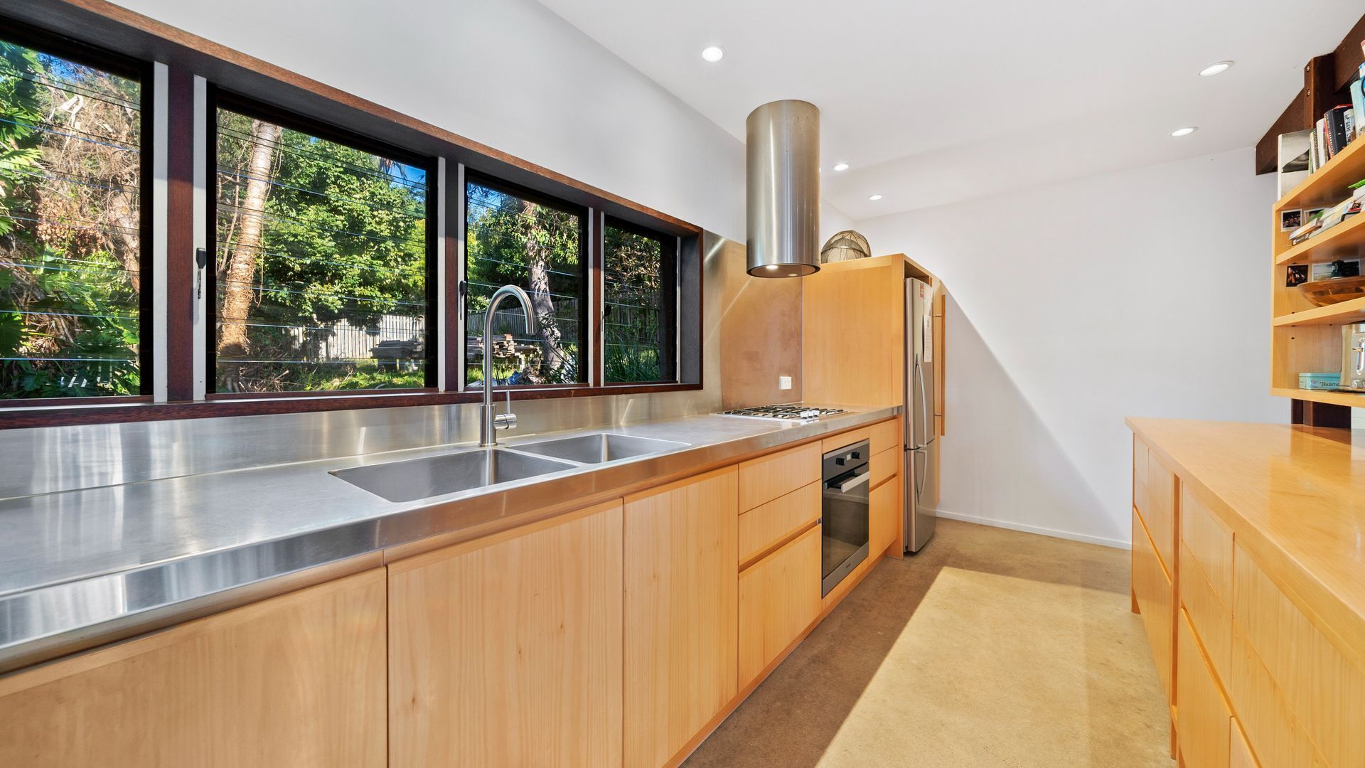 A modern kitchen with a large window, stainless steel appliances, and wooden cabinets.