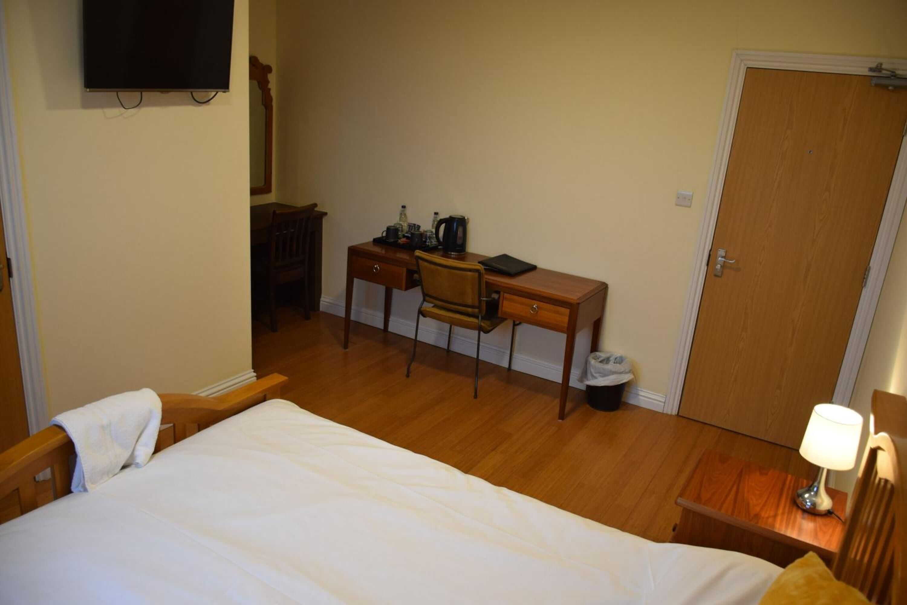 Een hotelkamer met een bed, een bureau, een stoel, een televisie en een deur.